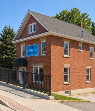 Red brick campaign office with Early for Mayor sign at 26 Queen St. South, Bolton